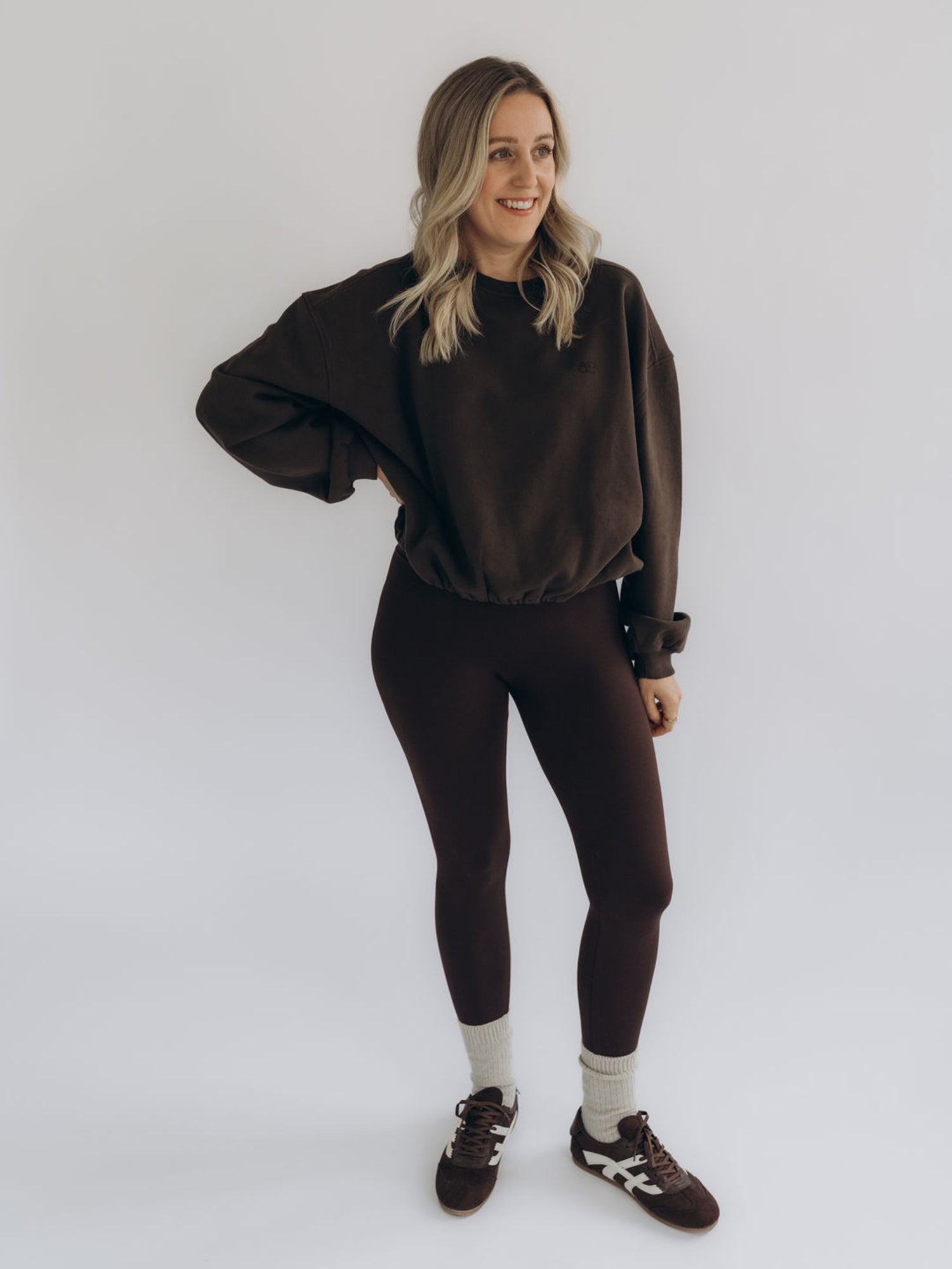 Michi trägt den dunkelbraunen Sweater LAURA 2.0 in einer frontalen Ganzkörperansicht.