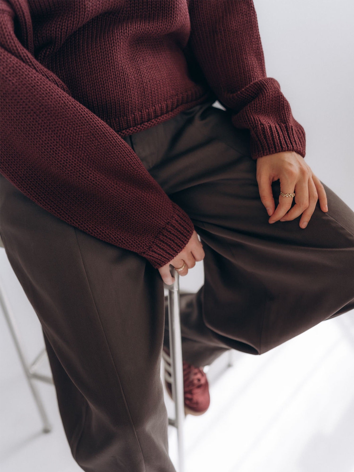 Nahaufnahme des getragenen Pullovers mit langen Ärmeln, Rippbündchen und sichtbarer Maschenstruktur.