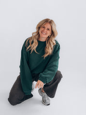 LAURA 2.0 in kniender Pose, kombiniert mit dunkelgrauer Jeans und Sneakern