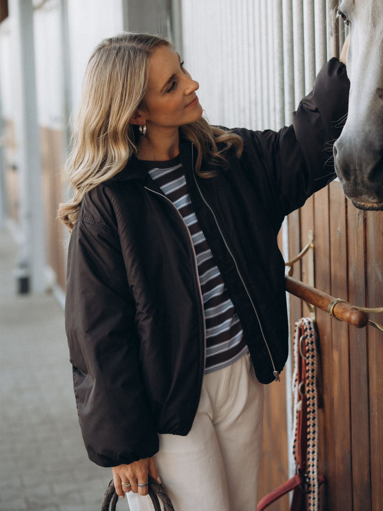 Tragebild Lisa mit der braunen Jacke LOVISA, gestreiften Longsleeve CARA und weißer Jeanshose