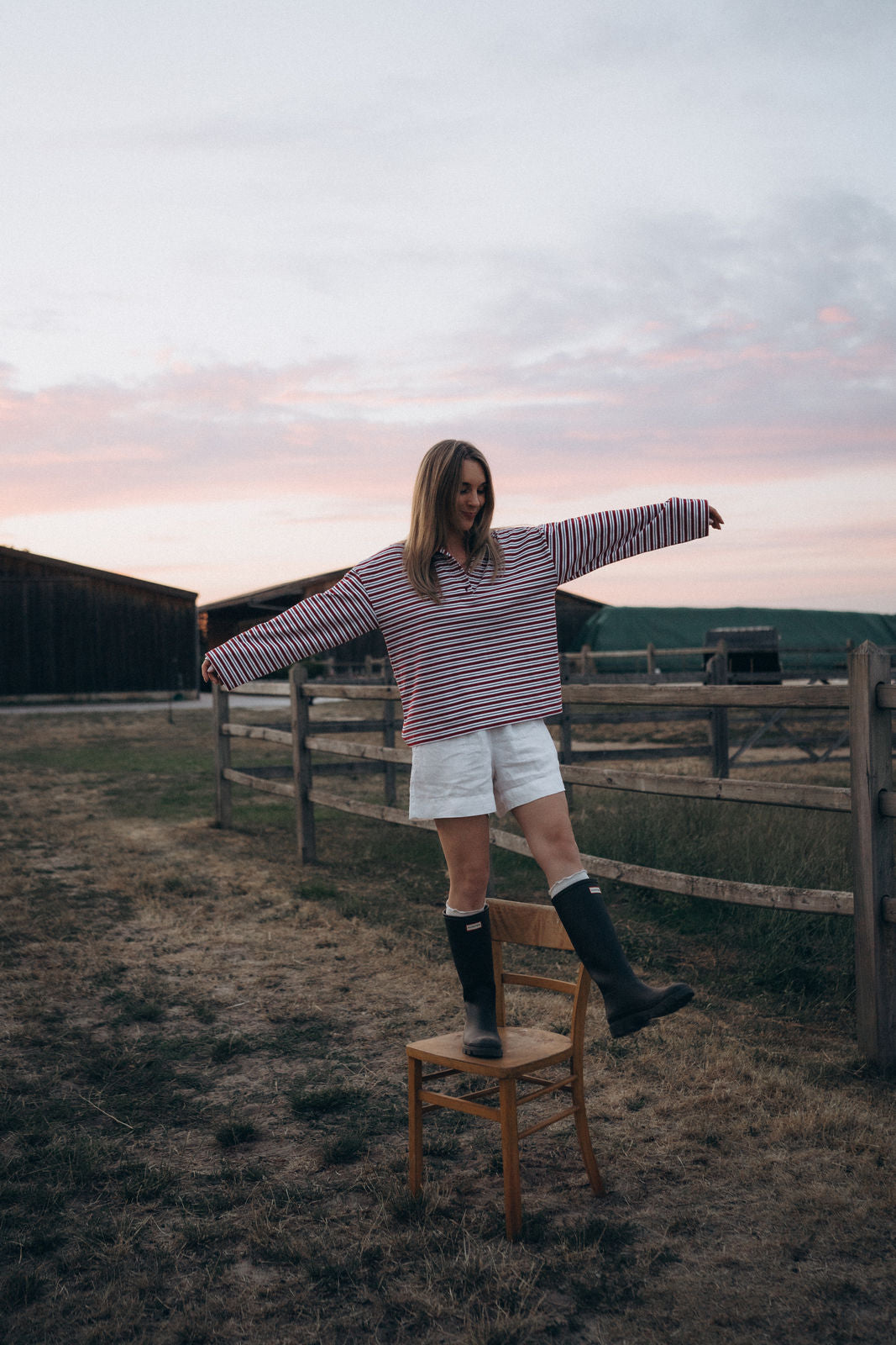 Lisa mit gestreiftem Longsleeve NORA vor einer Bauernhof Kulisse